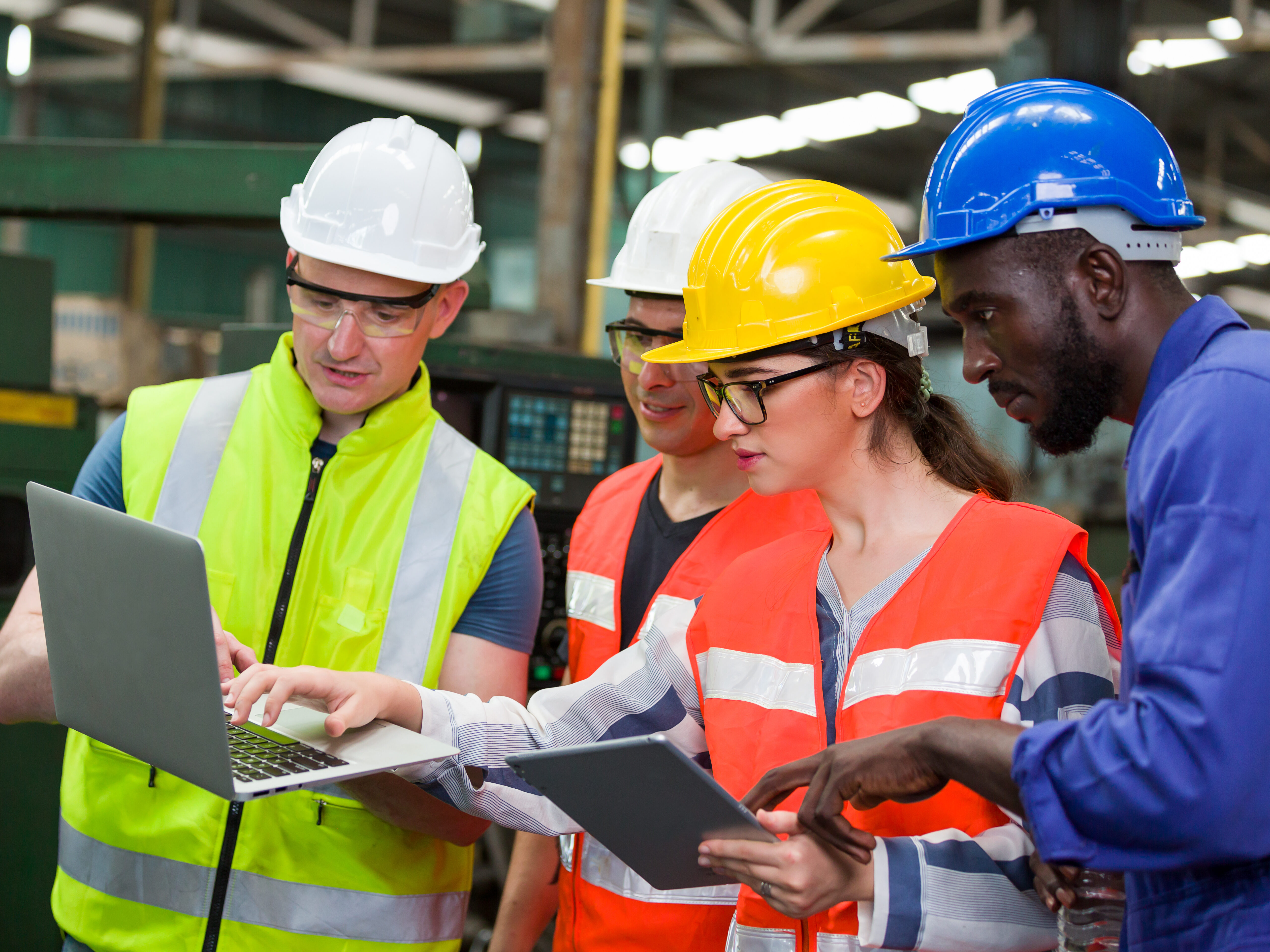 Group of workers in safety gear looking at a laptop.